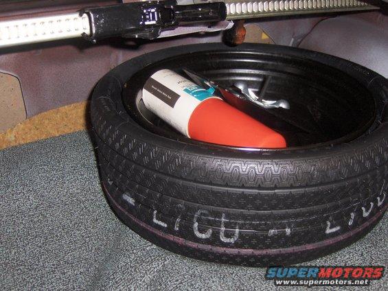 Spare tire and jack in trunk with white writing on tire sidewall