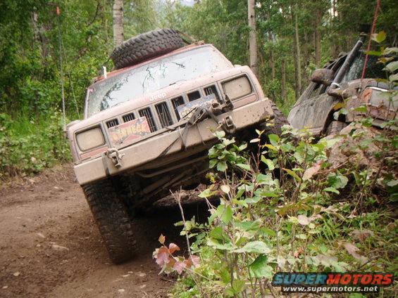 1998 Jeep Cherokee tilted on a muddy trail with another vehicle partially visible to the right