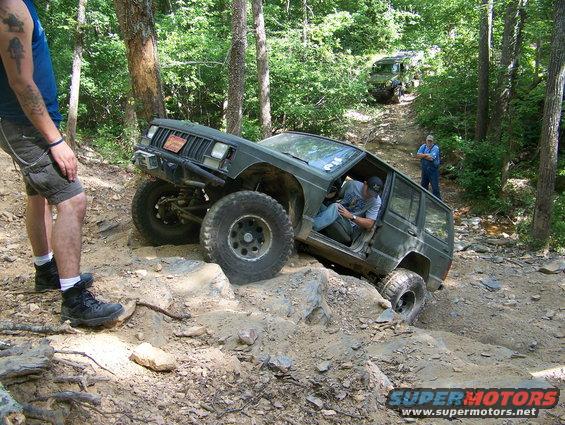 Jeep Cherokee XJ climbing rocky trail, driver inside, another Jeep behind