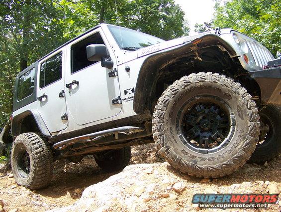 White Jeep Wrangler on a rocky trail, showing off its large tires and side steps