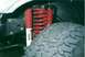 1990 Ford Bronco - Close-up of vehicle suspension components, including a Rancho shock and red coil spring.