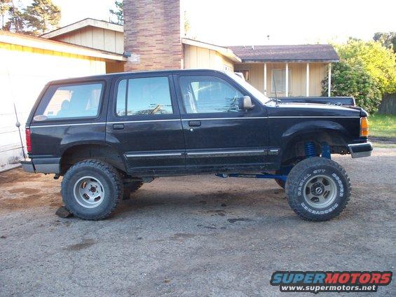 Black lifted SUV with off-road tires and blue suspension components