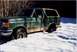 1990 Ford Bronco - A green 1990 Ford Bronco is stuck in deep snow, with only the top of the tires visible.