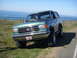 1990 Ford Bronco - 1990 Ford Bronco parked on a coastal road with the ocean in the background.