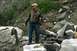 1990 Chevrolet Suburban - A man stands in a rocky outdoor environment, wearing a camouflage jacket and jeans.