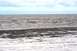 1990 Chevrolet Suburban - A calm day at the beach with gentle waves lapping the shore under a partly cloudy sky.