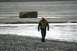 1990 Chevrolet Suburban - A man walks across a desolate, rocky landscape near a body of water.
