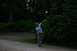 1990 Chevrolet Suburban - A person is captured mid-throw as they toss a ball in a park setting surrounded by trees.
