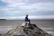 1990 Chevrolet Suburban - A person sits on a large rock formation overlooking a body of water under a cloudy sky.