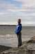 1990 Chevrolet Suburban - A young woman stands on a rocky shoreline with the ocean and cloudy sky in the background.