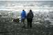 1990 Chevrolet Suburban - Two individuals observe the tide at a rocky and muddy coastal area.