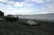 1990 Chevrolet Suburban - A person stands next to a green SUV parked on a rocky shore with the ocean in the background.