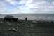 1990 Chevrolet Suburban - A person stands on a rocky beach next to an older SUV, with the ocean stretching out to the horizon under a cloudy sky.
