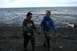 1990 Chevrolet Suburban - Two women wearing waders walk together on a rocky beach near the ocean.