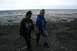 1990 Chevrolet Suburban - Two people walk on a rocky shore near the ocean under a cloudy sky.