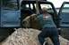 1990 Chevrolet Suburban - Man helps load a large rock into the back of a blue SUV.