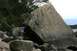 1990 Chevrolet Suburban - A person stands next to a huge boulder on a rocky shore, with trees and water in the background.