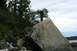 1990 Chevrolet Suburban - People explore a rocky shoreline with trees and water in the background under a cloudy sky.