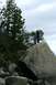 1990 Chevrolet Suburban - Two individuals are positioned atop a prominent rock, with a backdrop of trees and an overcast sky.