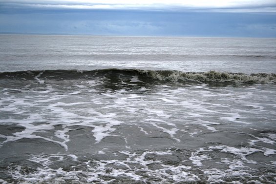 Waves crashing on the shore under a cloudy sky