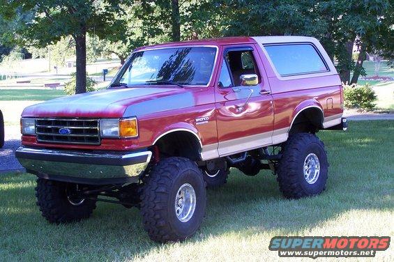 1990 Ford Bronco, red with tan stripe, lifted suspension, large off-road tires