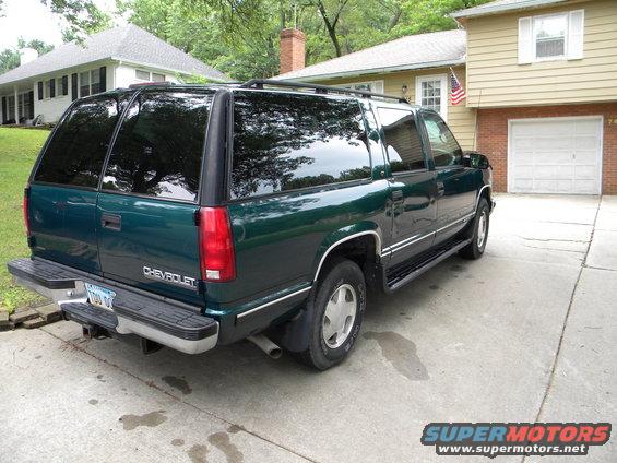 1999 Chevrolet Suburban, rear 3/4 view, parked in driveway. Green paint, tinted windows