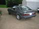 1985 Ford Mustang - A gray 1985 Ford Mustang hatchback is seen from a 3/4 front angle, parked on a dirt surface with a tent and another vehicle in the backgrou…