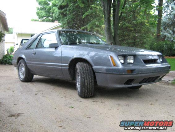 Gray 1985 Ford Mustang hatchback parked on a dirt driveway