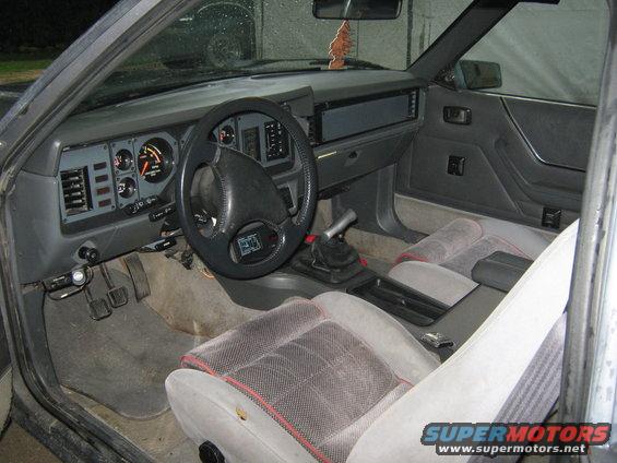 1985 Ford Mustang interior showing dashboard, steering wheel, seats, and gear shifter