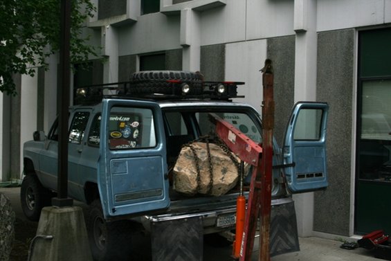 blue SUV with roof rack and spare tire, doors open, rock chained in bed with engine hoist
