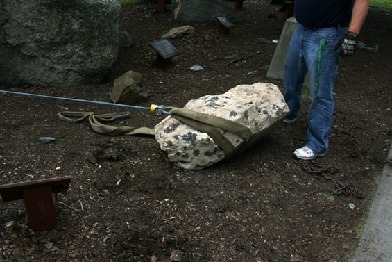 Rock with straps and tow cable on the ground, a person stands nearby
