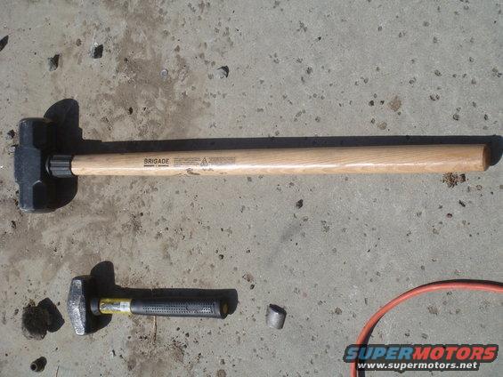 Two sledgehammers, one large and one small, on a concrete surface
