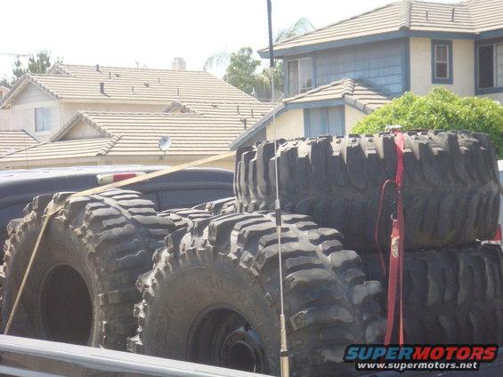 Several large off-road tires stacked in a truck bed