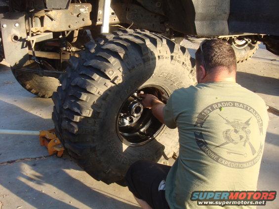 Man working on a large off-road tire and wheel