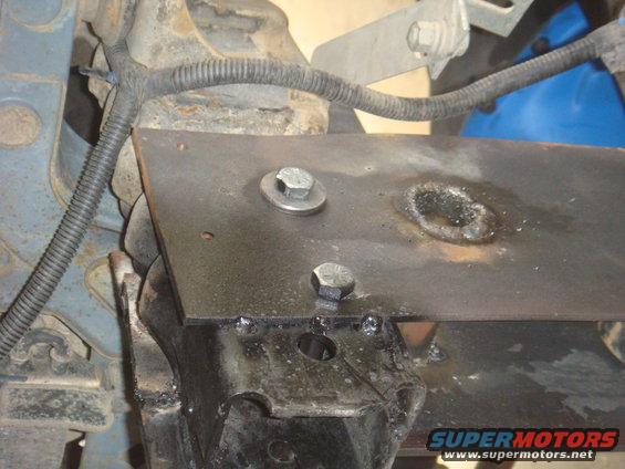 Custom metal bracket welded to vehicle frame with bolts and wiring