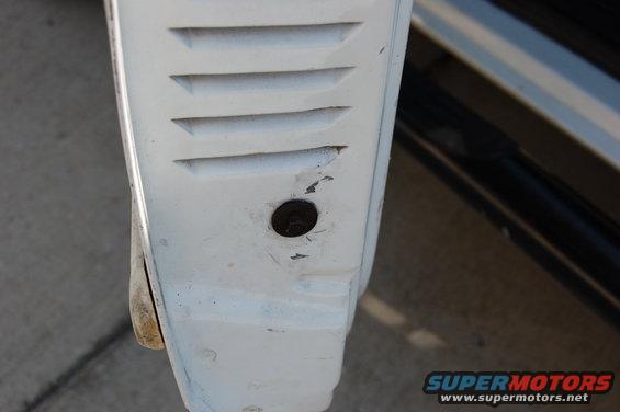 White vehicle fender with horizontal vents and a bolt hole. A black bar is visible to the right