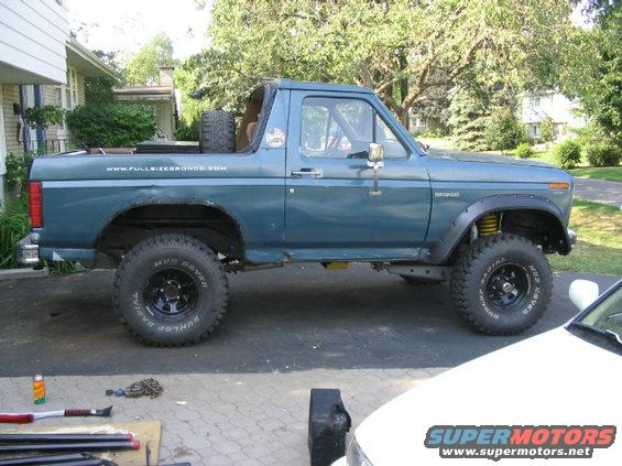 Blue lifted 1986 Ford Bronco side view with website www.fullsizebronco.com on the bed