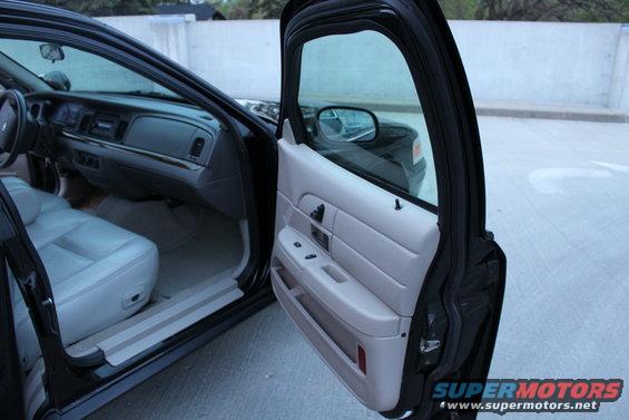 Interior of a 2007 Ford Crown Victoria, showing the dashboard, driver's seat, and open front passenger door