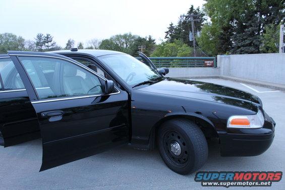 Black 2007 Ford Crown Victoria sedan with front passenger door and driver's door open, parked on asphalt
