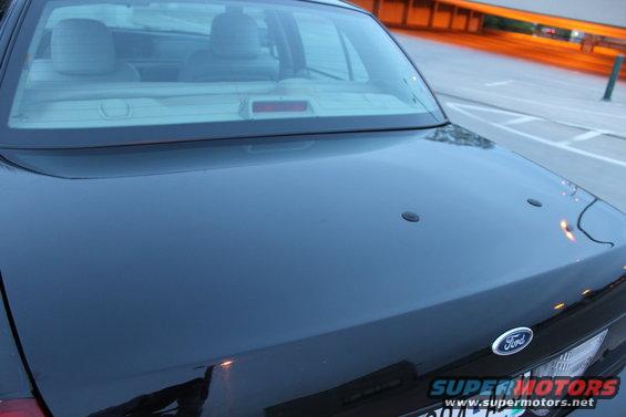 Black sedan trunk with Ford emblem. Rear window shows interior