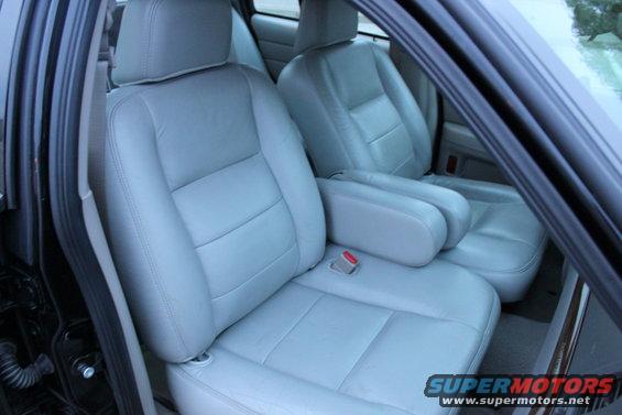 Light gray leather front seats and center console with armrest. A red seatbelt buckle is visible