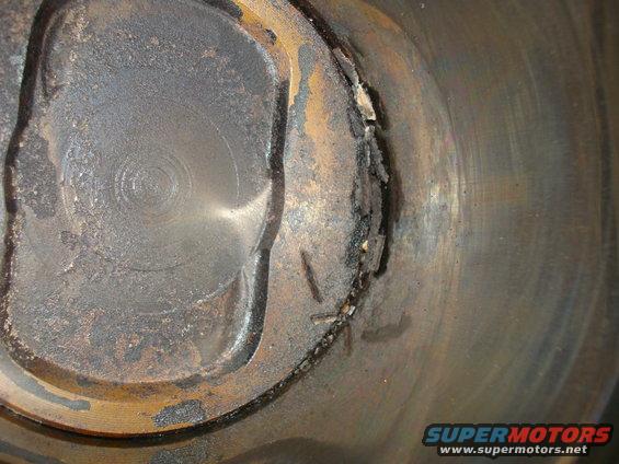 Close-up of a damaged piston with carbon buildup and metal fragments