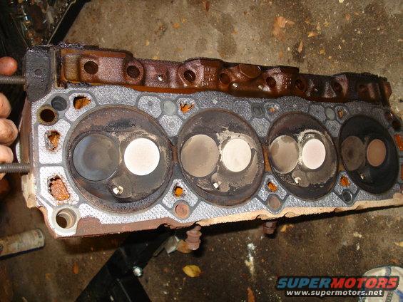 Rusty engine cylinder head with visible valves and combustion chambers
