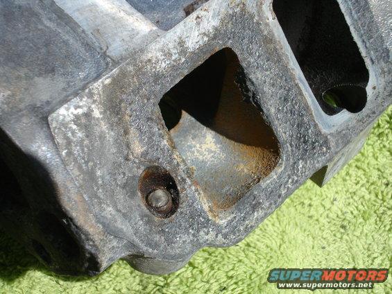 close-up of a dirty, cast metal engine intake manifold with square openings