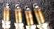 2010 Hyundai Genesis - Close-up of four spark plugs, showing wear and deposits on the electrodes.