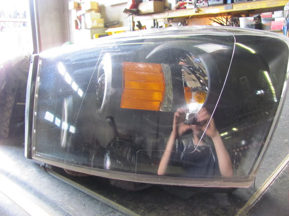 Headlight assembly with amber turn signal, clear lens, and black housing. Scratches visible on lens