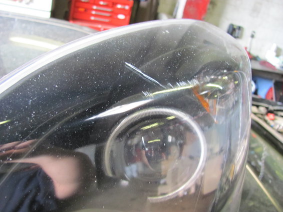 Close-up of a damaged headlight assembly with a scratch on the lens