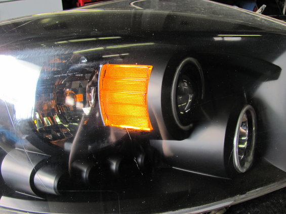 Black headlight assembly with amber turn signal and projector lens