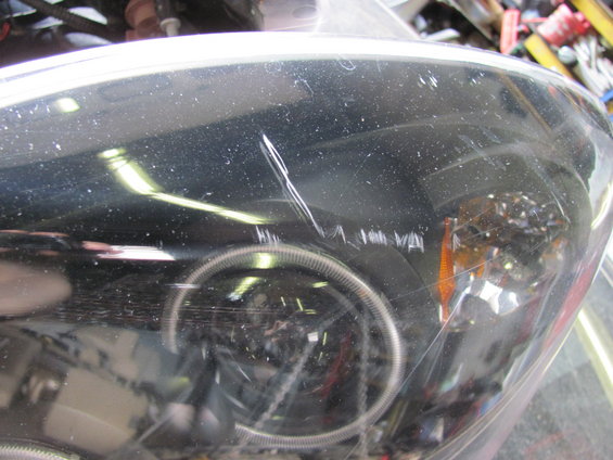 Close-up of a scratched headlight assembly with a halo ring