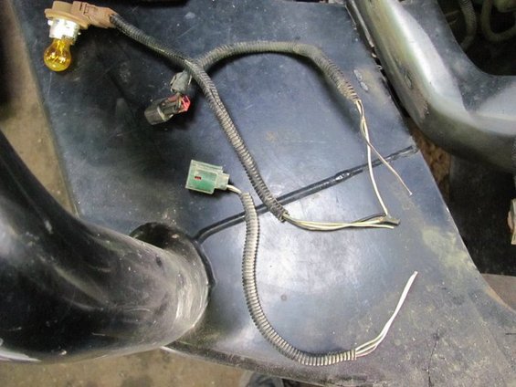 Wiring harness with a yellow bulb socket and two connectors, one green and one black with red insert. Wires are exposed